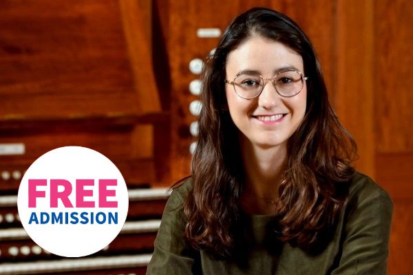 Organist Ophelia Amar sat smiling at an organ