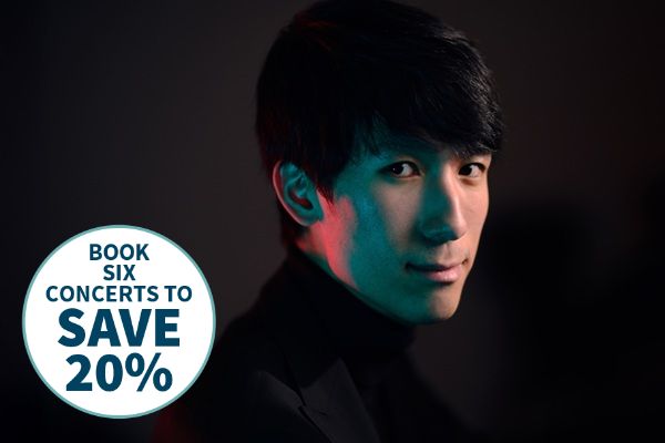 Pianist Eric Lu in a black high neck top with different coloured lights on his face.