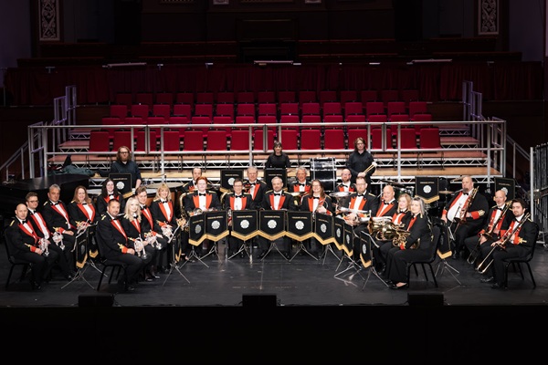 Members of the Yorkshire Imperial Band in black and red concert dress sat in formation with their instruments.