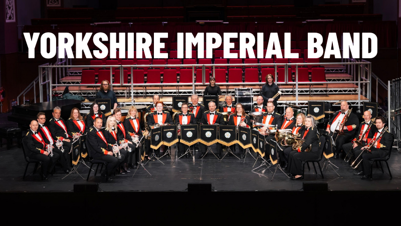 Members of the Yorkshire Imperial Band in black and red concert dress jackets sat in formation with their brass instruments.