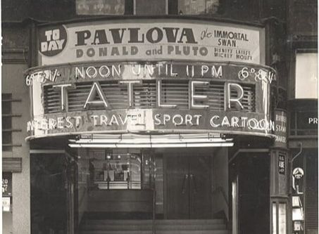 A black and white image of an old cinema called "Tatler" with bright neon lettering across the front. 