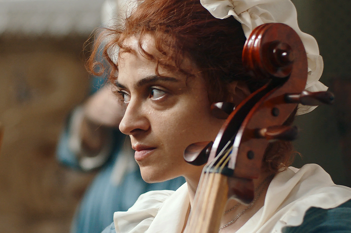 Still from Gloria! A woman looks to the left holding a double bass.