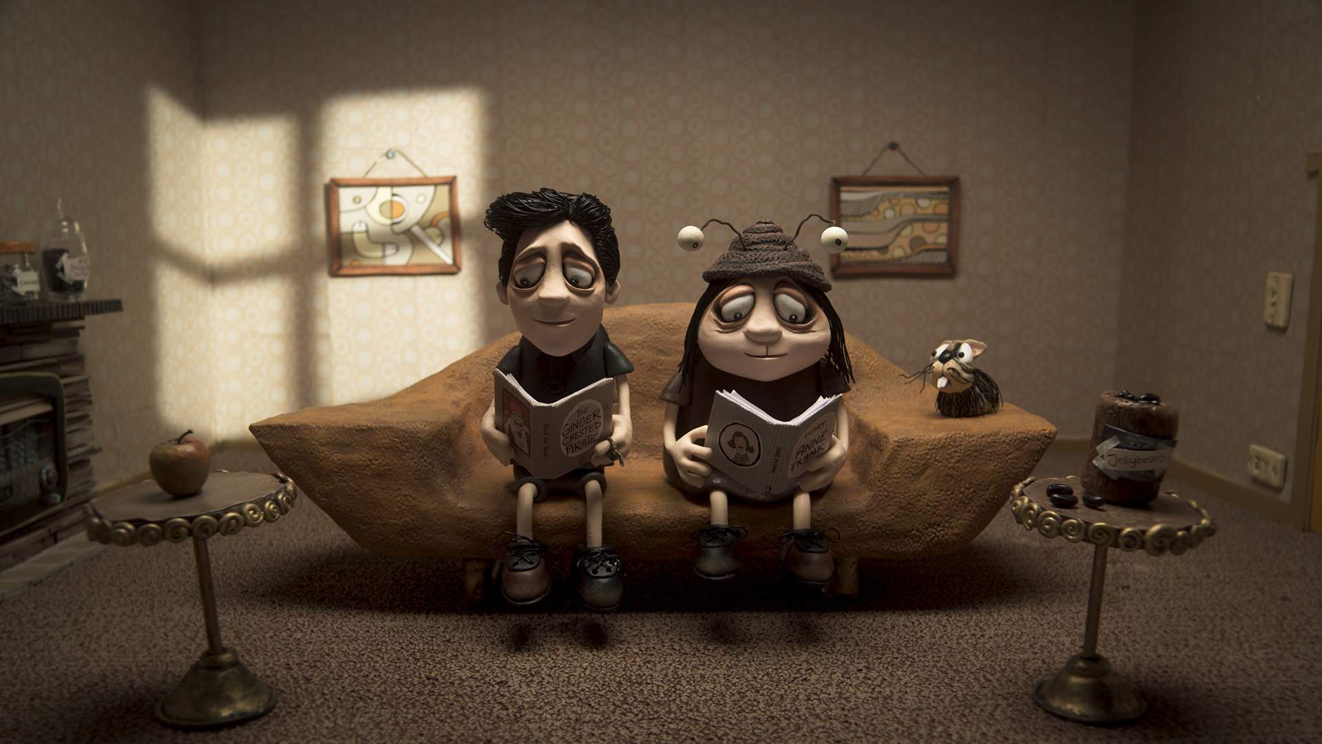 Still from Memoir of a Snail - two claymation characters sit on a sofa and read books.