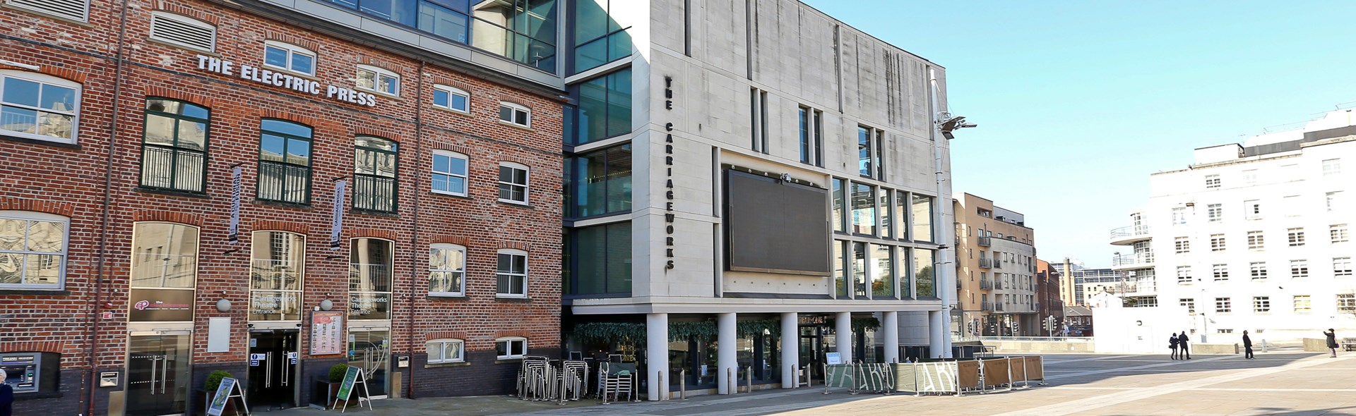 Exterior view of The Electric Press and The Carriageworks Theatre in Leeds, with a wide open square in front, taken during daylight.