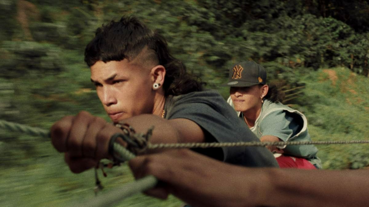 A close-up action shot of two young men pulling a rope outdoors, with motion blur suggesting speed and intensity.
