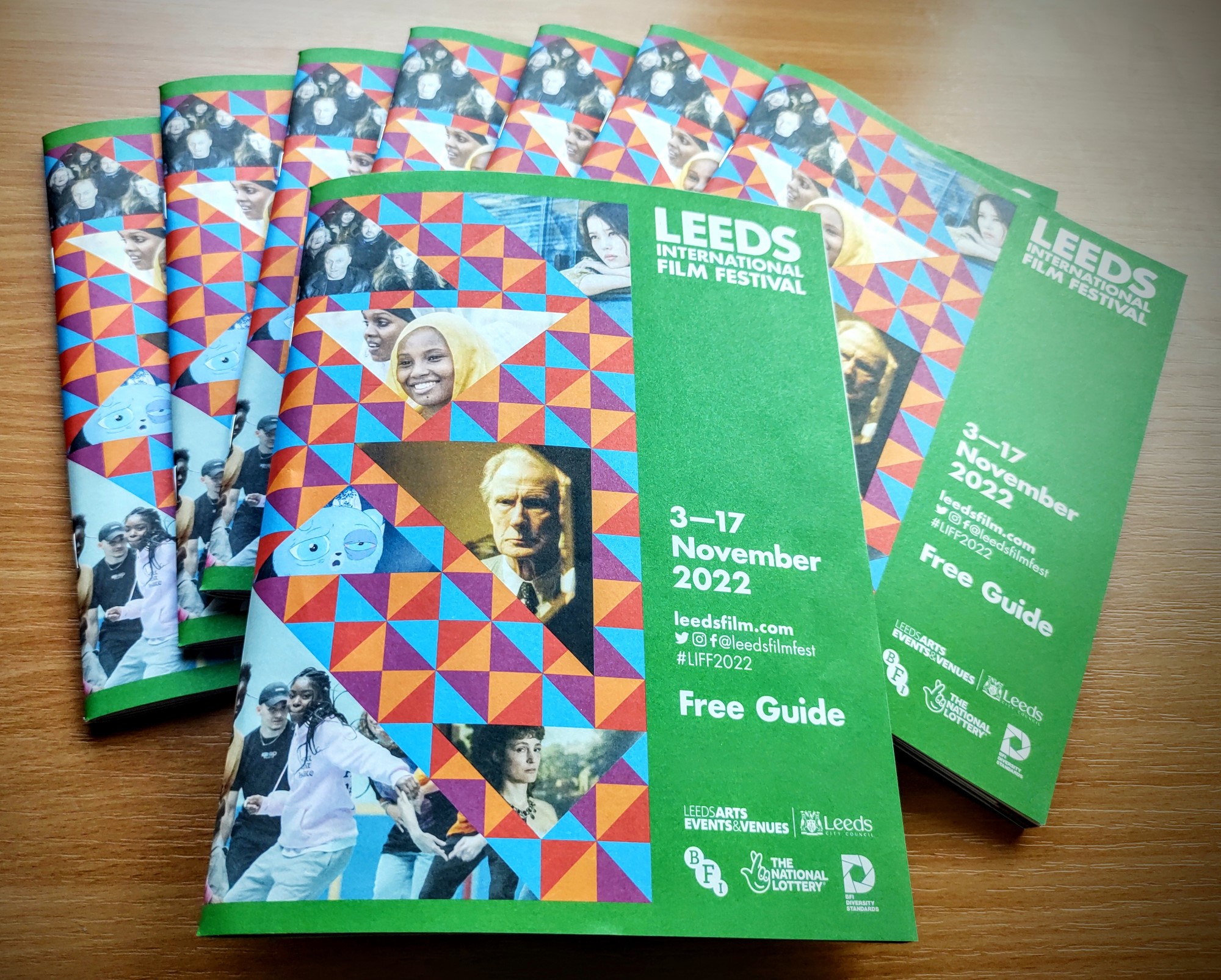 A stack of green coloured guides with images from various films and branded with the Leeds International Film Festival logo. 