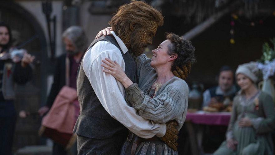 A middle aged women in period clothing dances intimately with a suited man made of wicker.