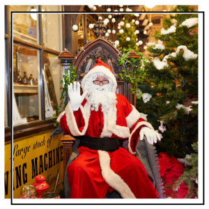 Santa in his grotto next to a christmas tree