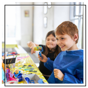 children wearing aprons doing a printing activity