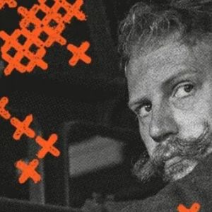 A black and white image of a male mill worker, looking over his shoulder. The image is overlayed with orange patterns