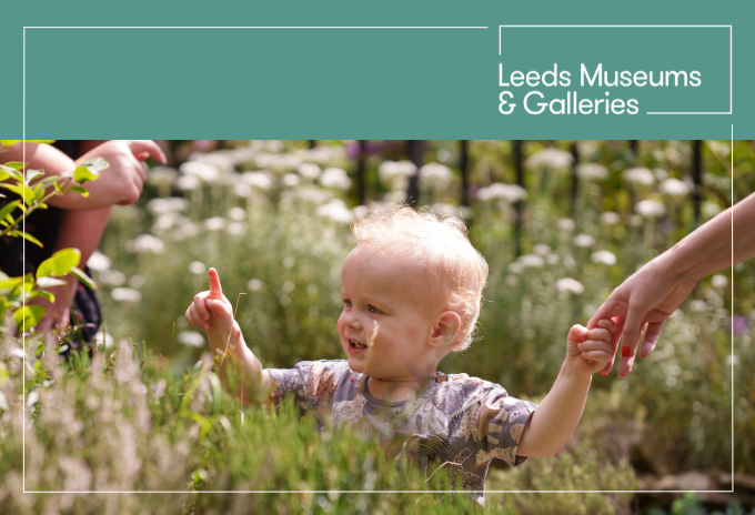 a baby sitting among grass and flowers in the colour garden at leeds industrial museum