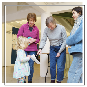 a little girl showing a piece of paper to her family and leeds art gallery volunteers