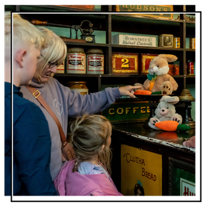 a family looking at cuddly toy bunnies in one of the shops in abbey house museum's victorian streets