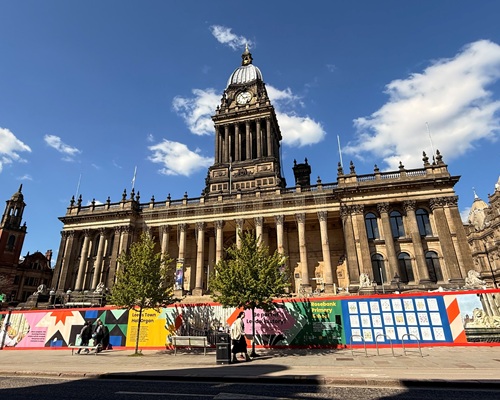 Leeds Town Hall in the sunshine surrounded by brightly coloured hoardings.