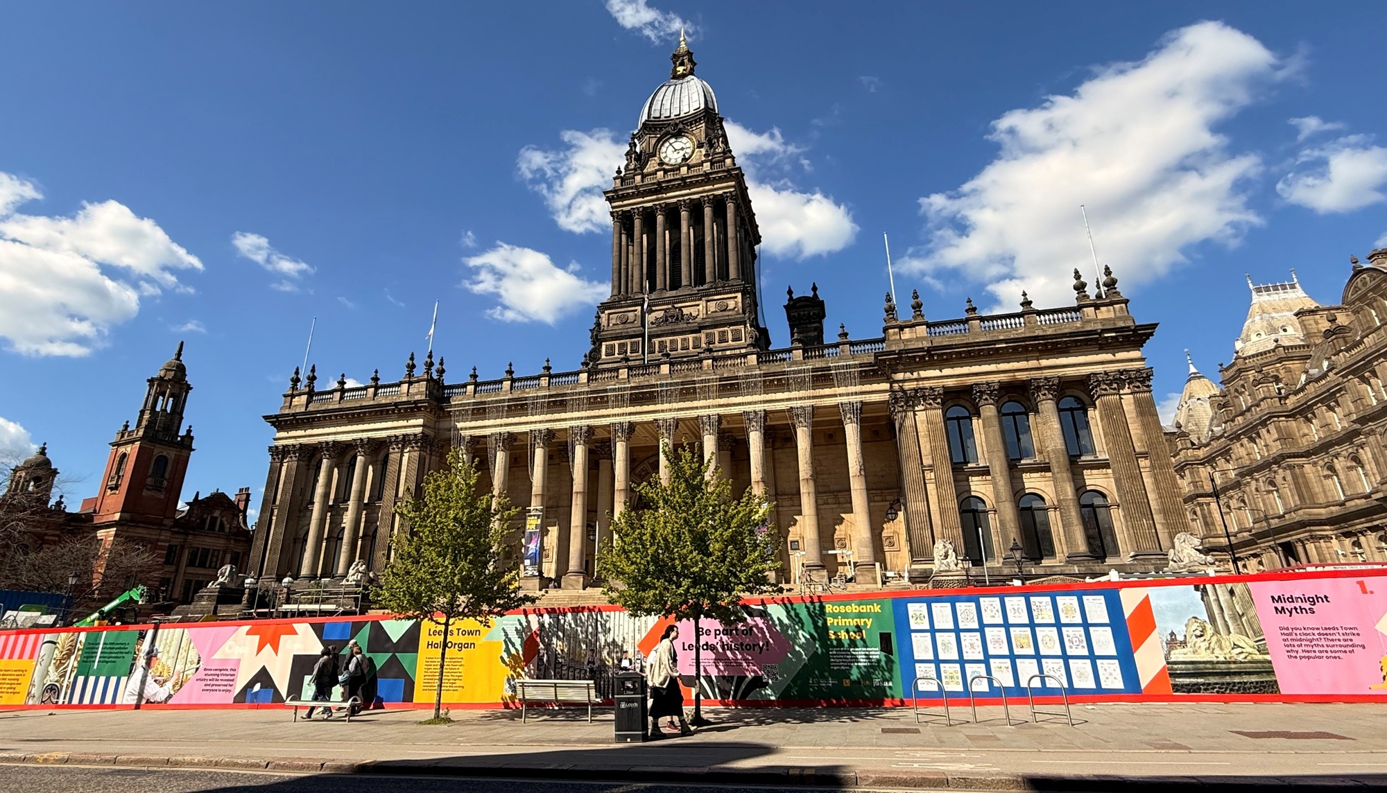 Leeds Town Hall and the colourful hoardings in the sunshine.