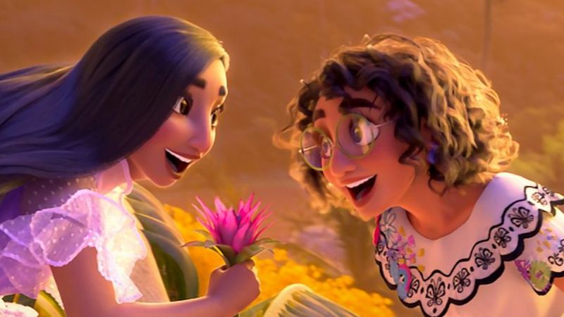 Isabela and Mirabel smiling in a bright floral setting.