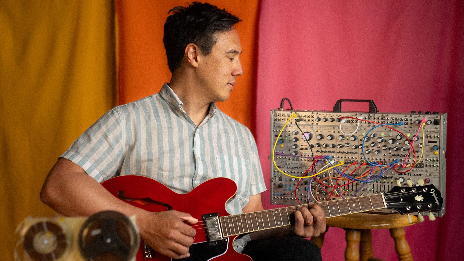 No-No Boy plays a guitar against a colorful background