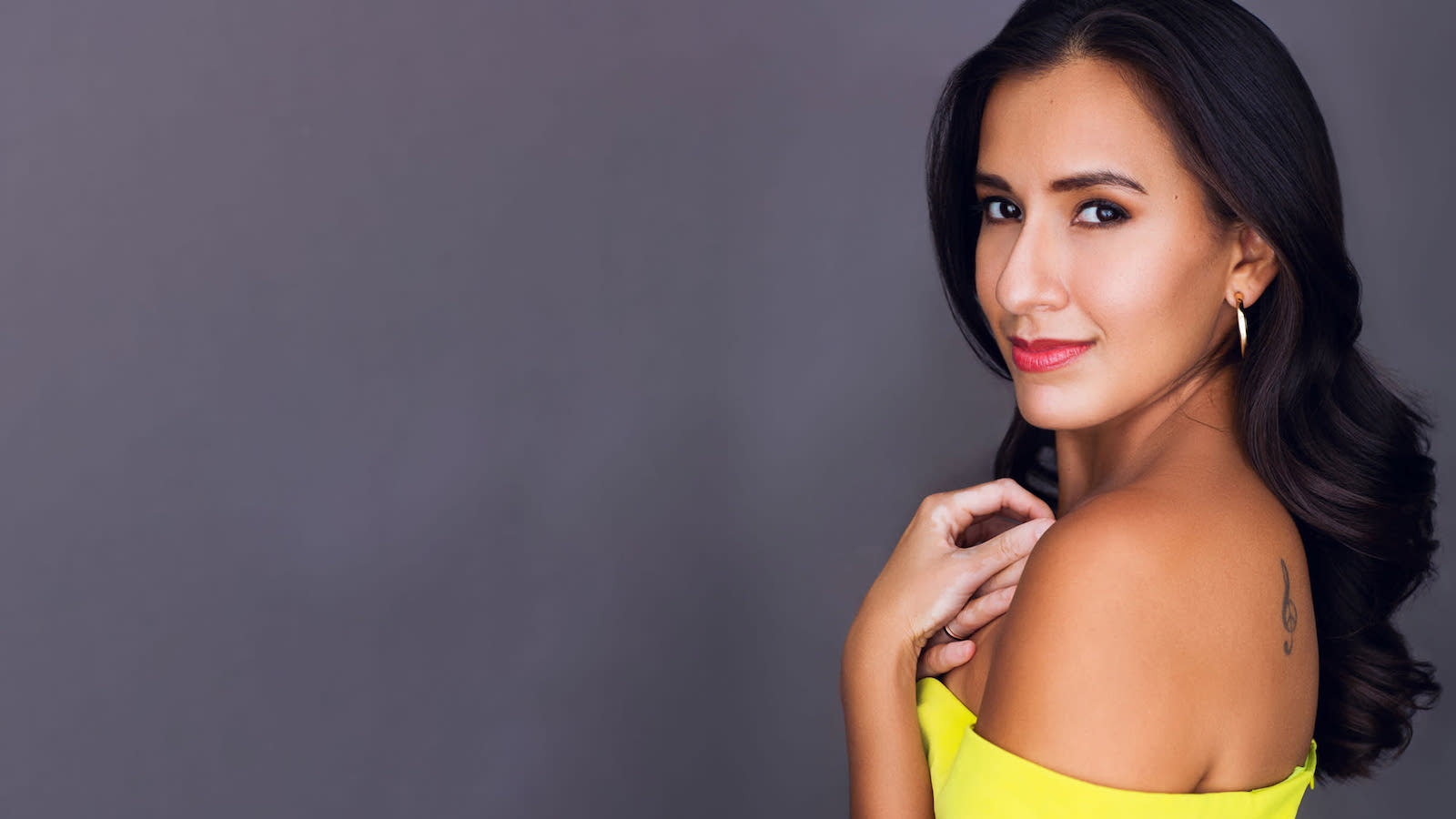 A woman with long black hair in a strapless yellow dress 