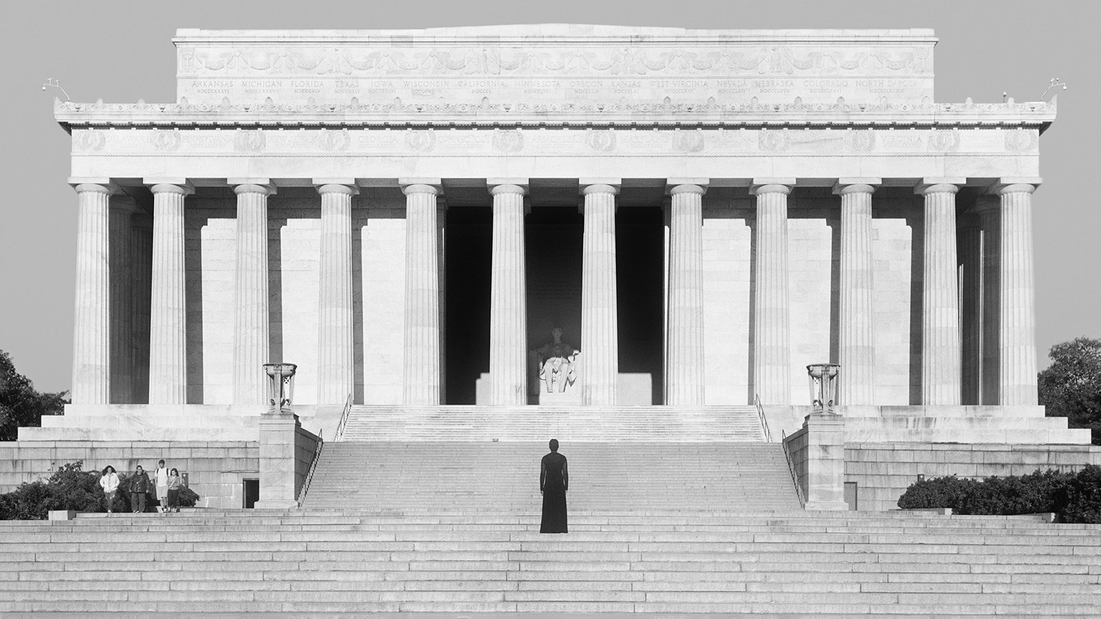 A woman stands in front of the towering Lincoln Memorial in a black and white photo
