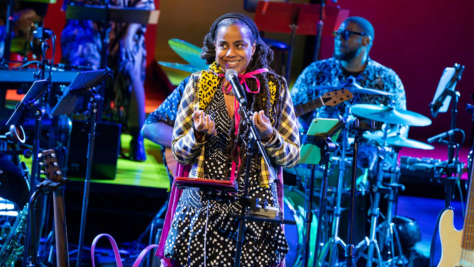 A woman in colorful clothes stands in front of her band