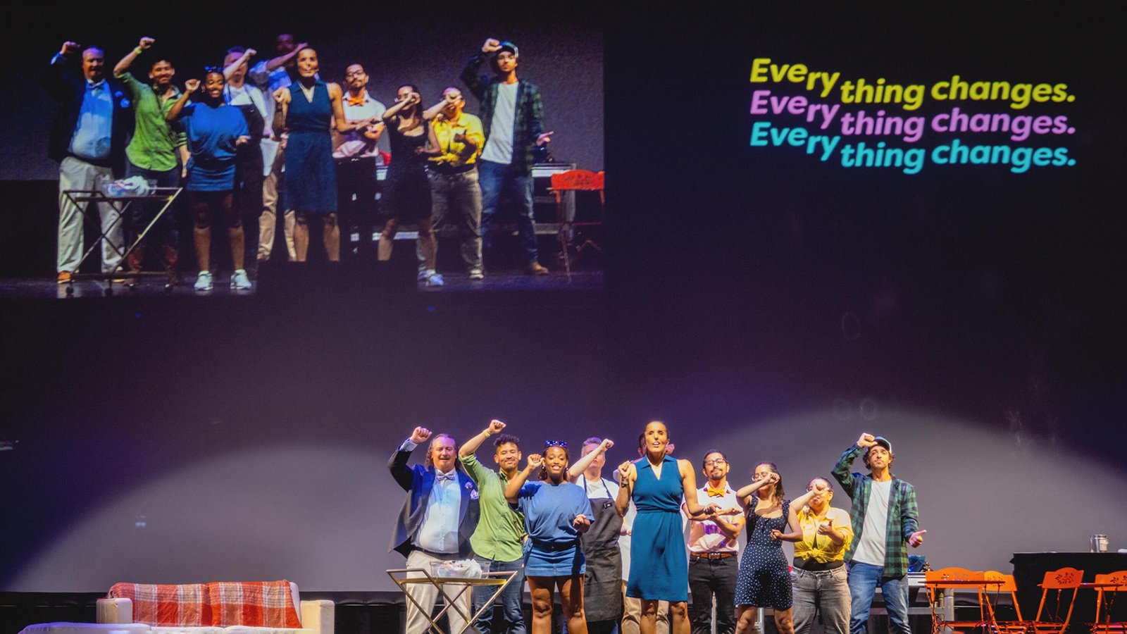 group of performers on stage with "everything changes" superimposed in the top left corner