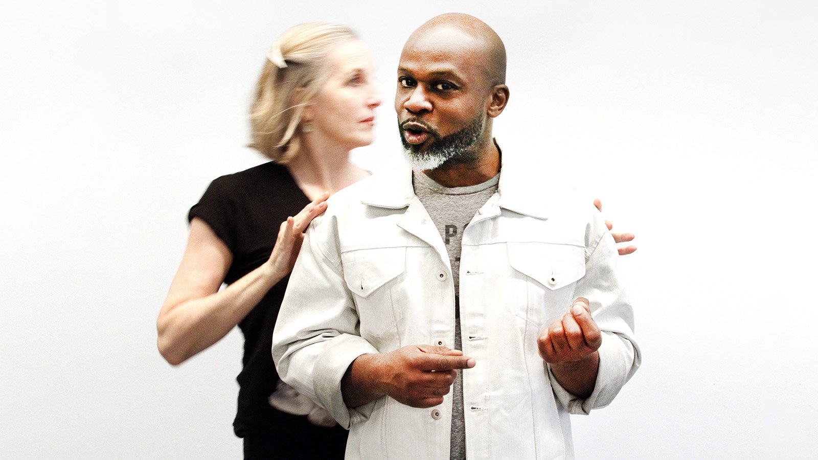 A man in a white coat standing next to a woman in a black shirt