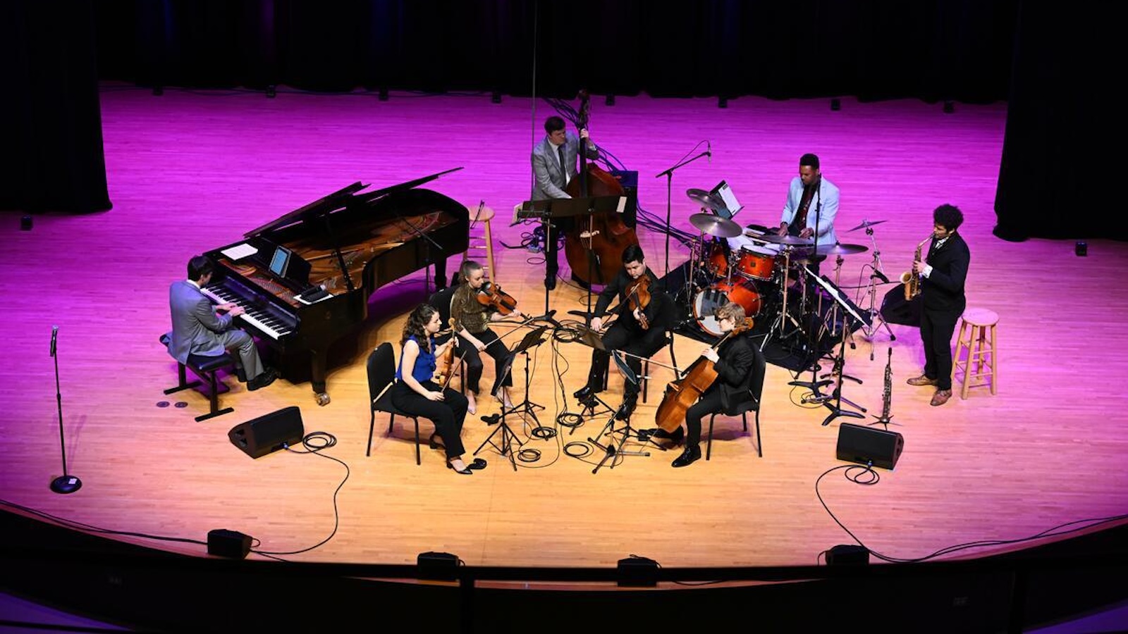 Chamber musicians on stage under pink lighting