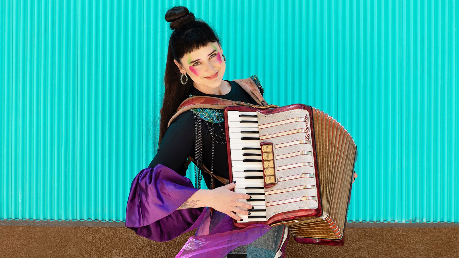 A woman with long black hair playing the accordion 