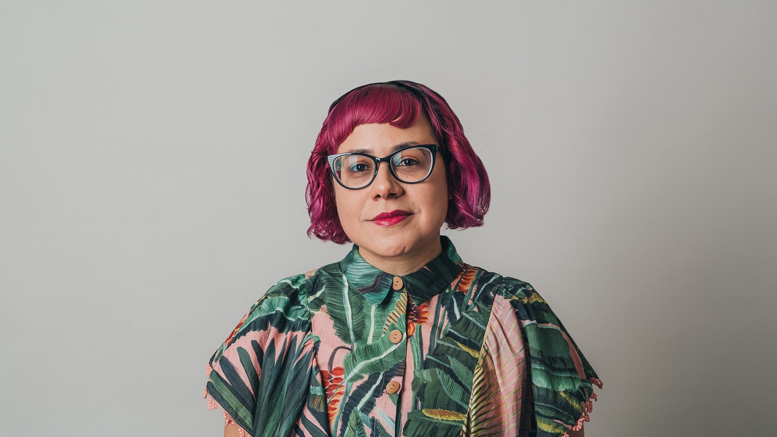 A woman with short red hair wearing a floral blouse 