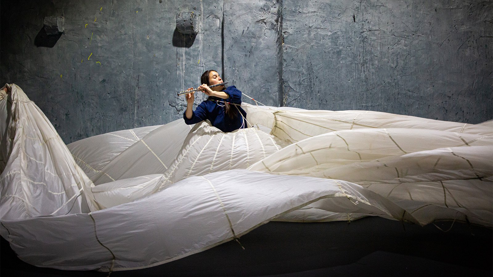 a woman playing the flute in a gigantic white, flowing skirt