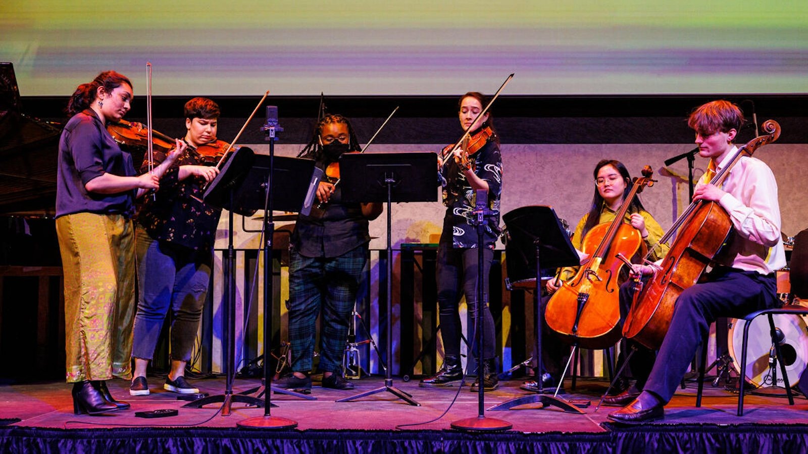 a group of young musicians on stage playing string instruments 