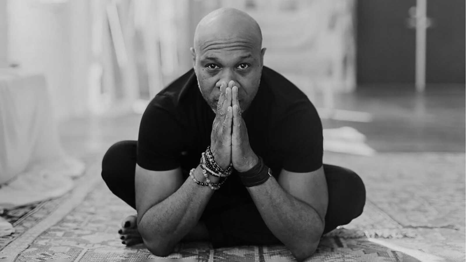 a man sat criss-cross with his hands in a prayer position in from of his face