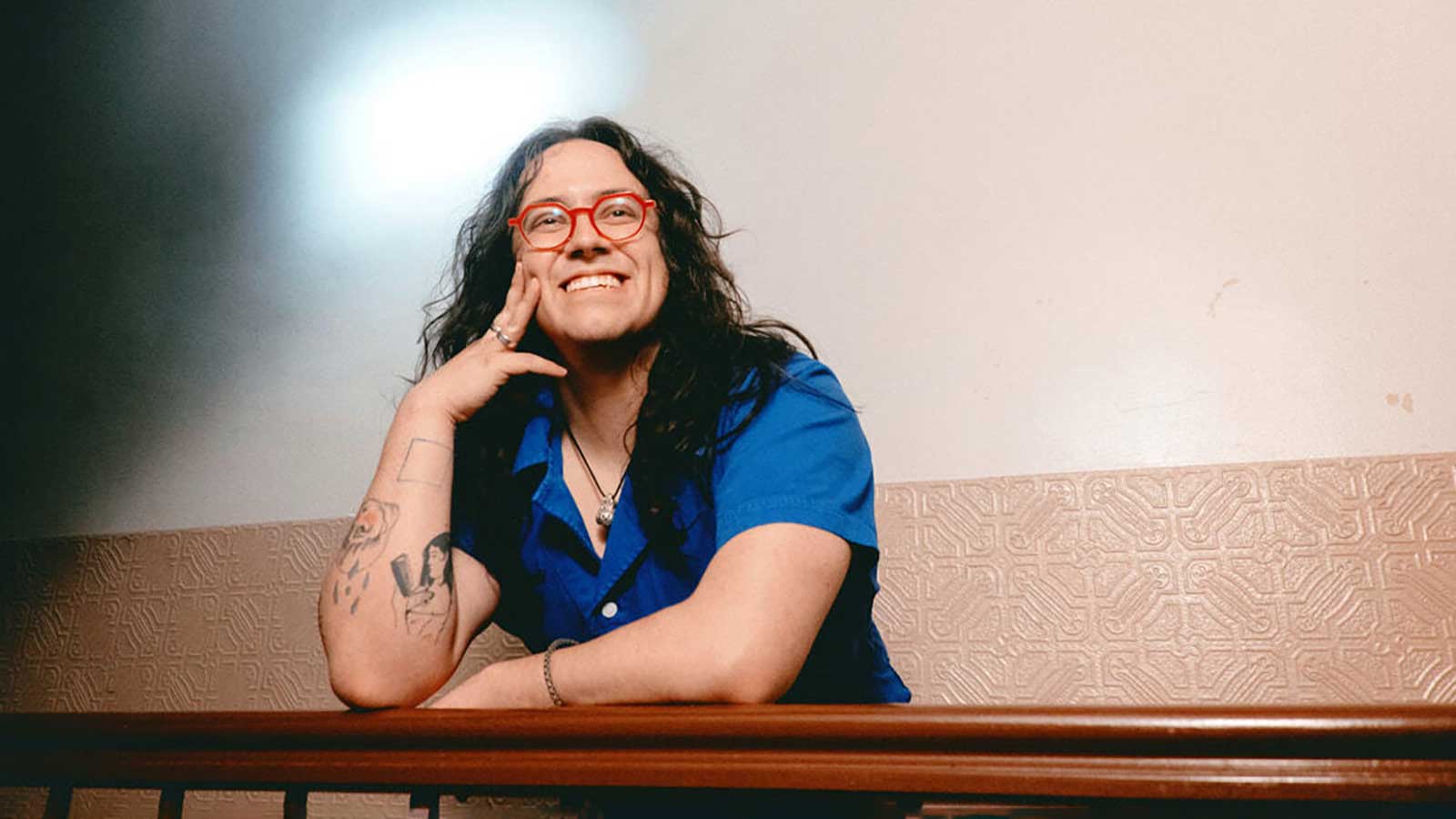 a person with long, dark hair and red-rimmed glasses