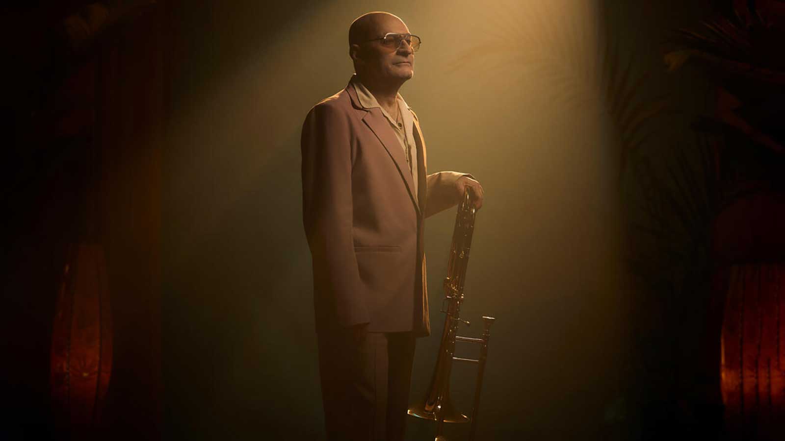 man in dramatic lighting holding an instrument