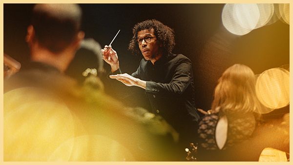 Jonathon Heyward conduts the orchestra with his baton raised