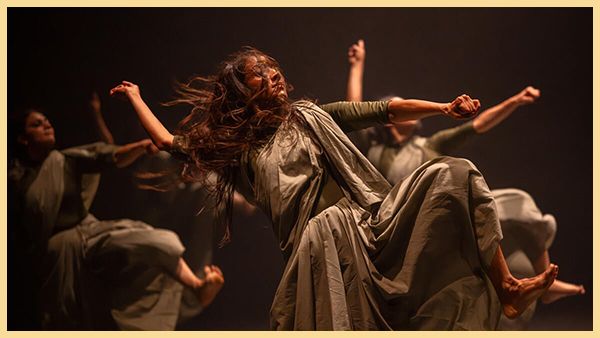 Dancers in flowing gray costumes lift their arms and legs