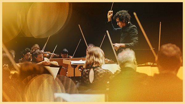 Jonathon Heyward conducts the orchestra with his baton raised