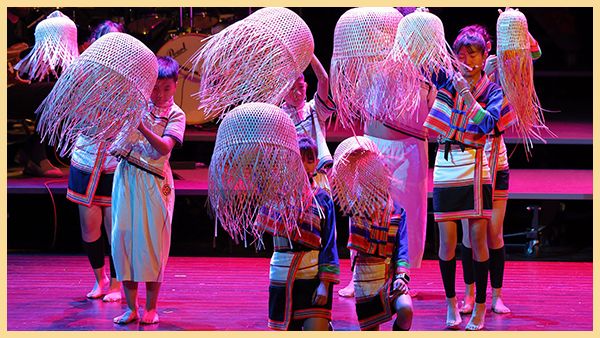 Young people hold baskets on a stage.