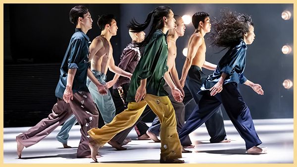 A group of dancers walk across a stage.