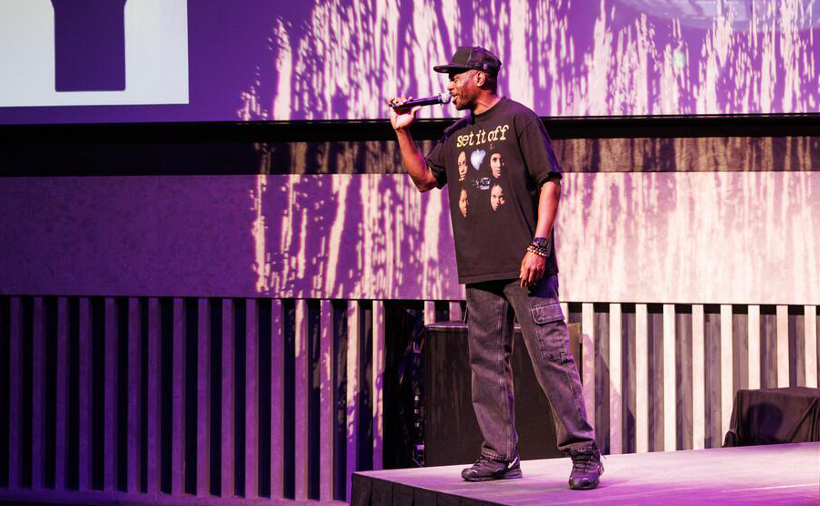 A man holds a mic and hypes up the crowd at the atrium