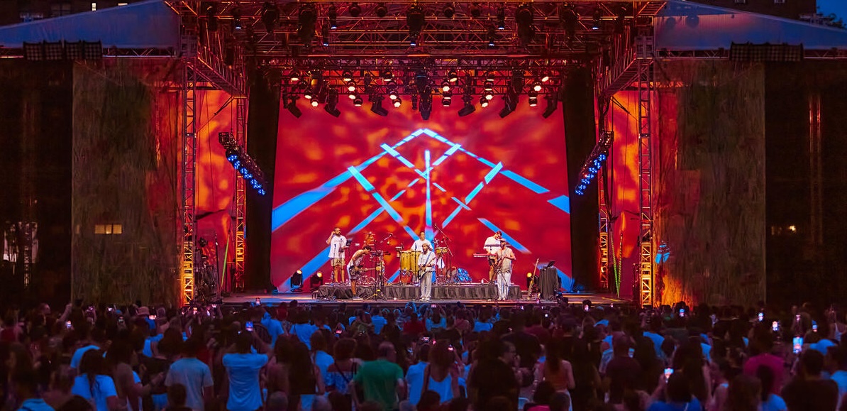 AN audience dances under a 10 ft disco ball