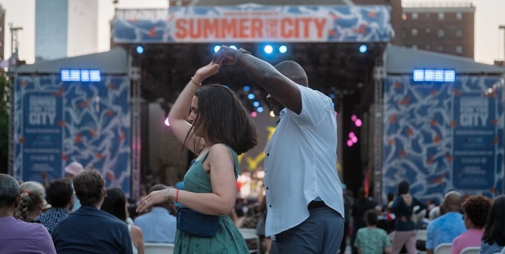 AN audience dances under a 10 ft disco ball