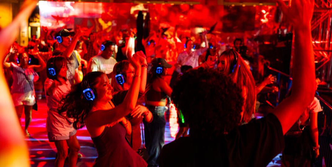 A woman stands under blue light, holding a guitar