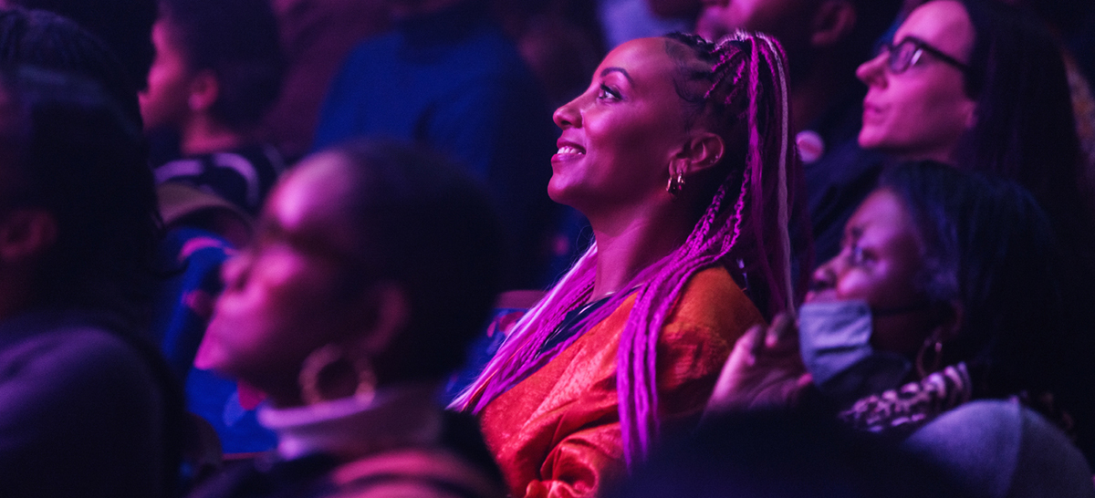 A woman in an audience smiles at the stage
