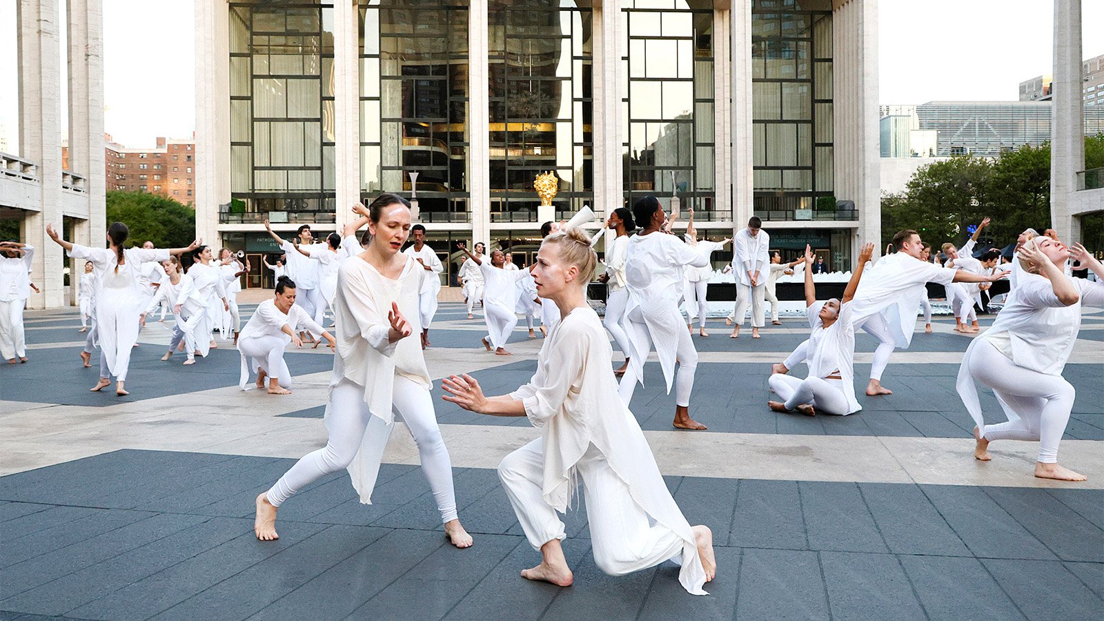 A group of dancers dressed in white move across Josie Robertson Plaza