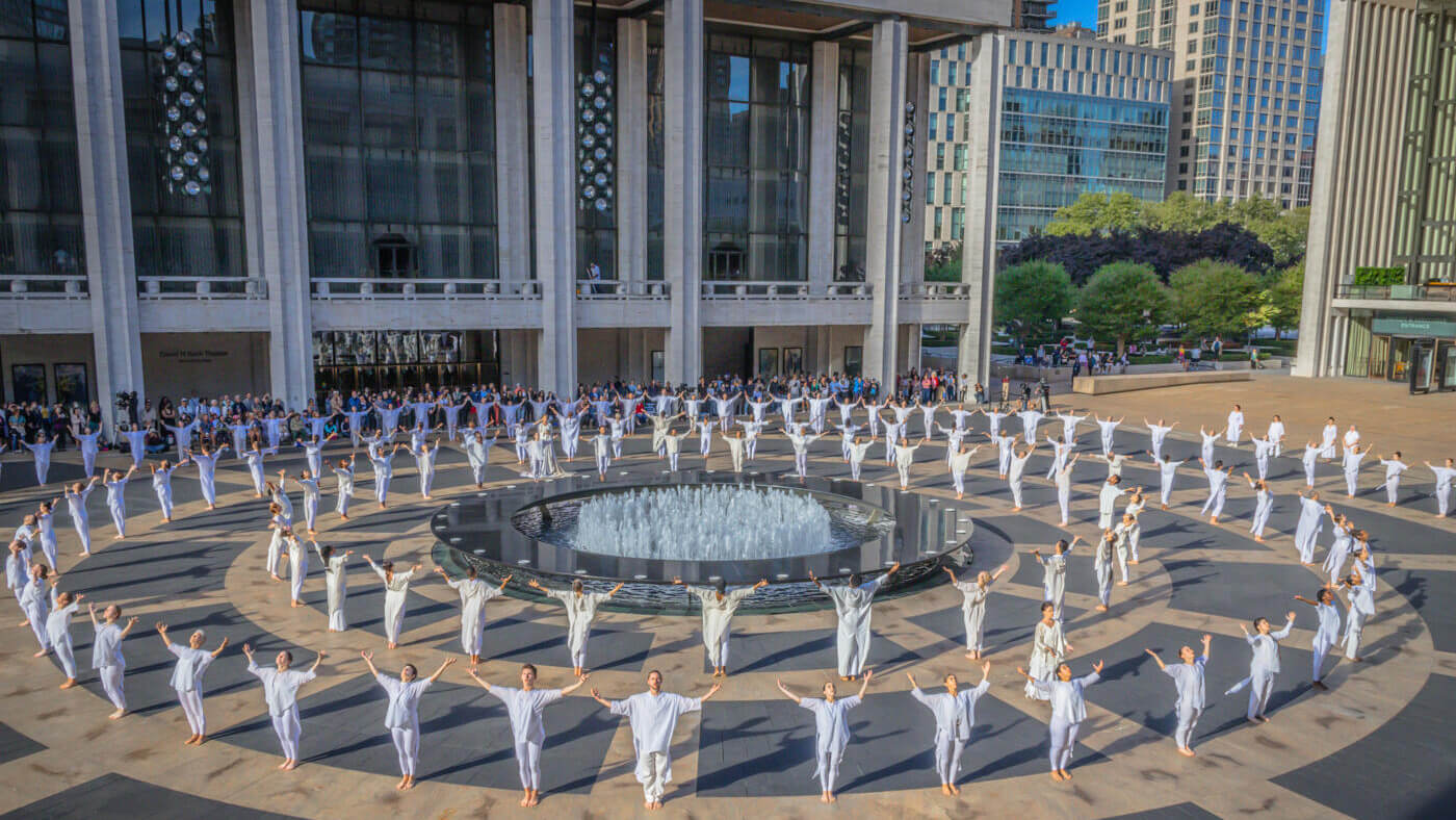 Three large rings of dancers dressed all in white surround the fountain in Josie Robertson Plaza