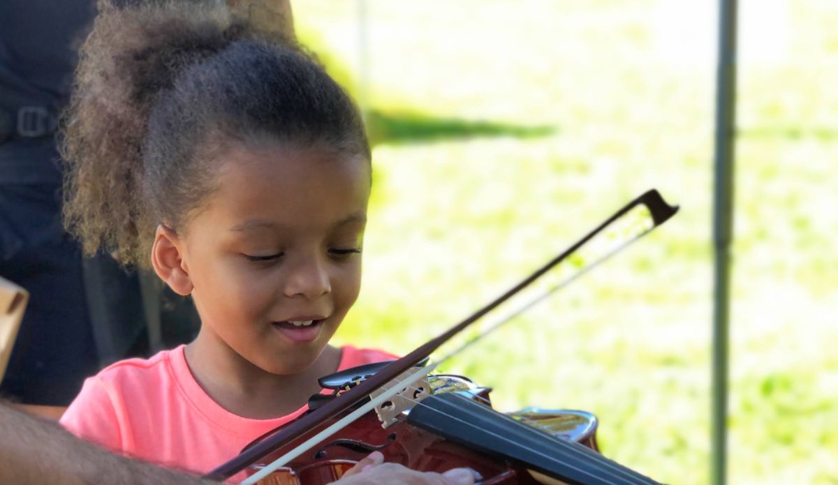 A young girl holds a violin