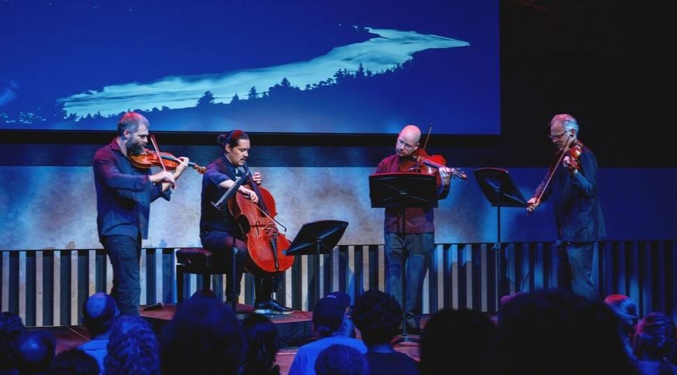 Brooklyn Rider, a string quartet, performs at the Atrium under blue lights