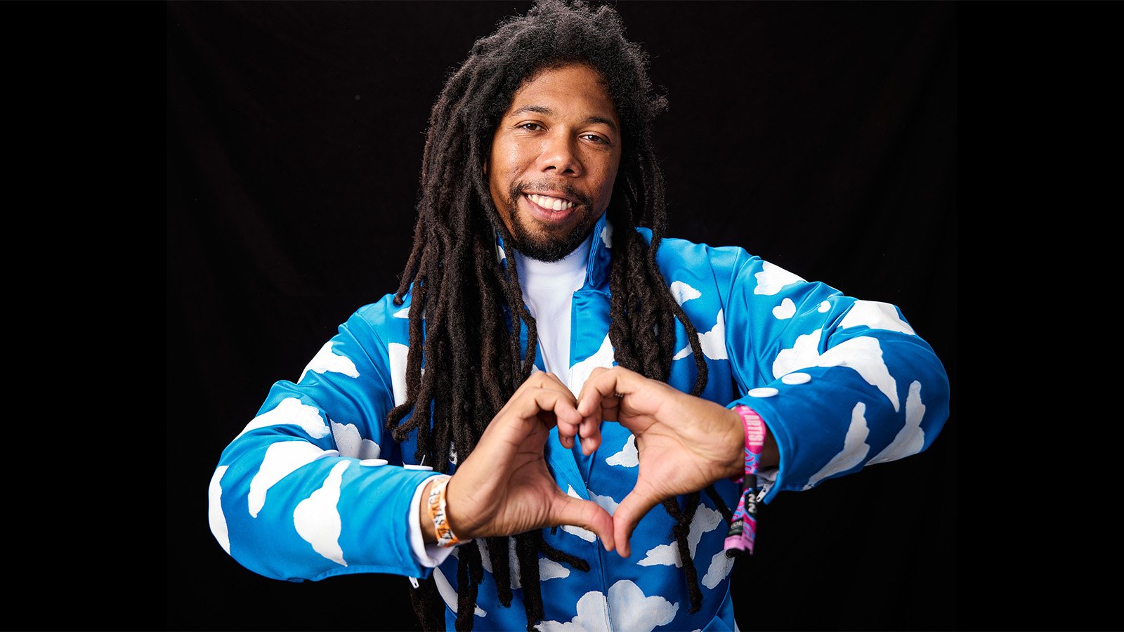 A teenage girl with braces holds up a sign that says "PROM QUEEN" with the letter & R spray-painted over the N, spelling PROM QUEER