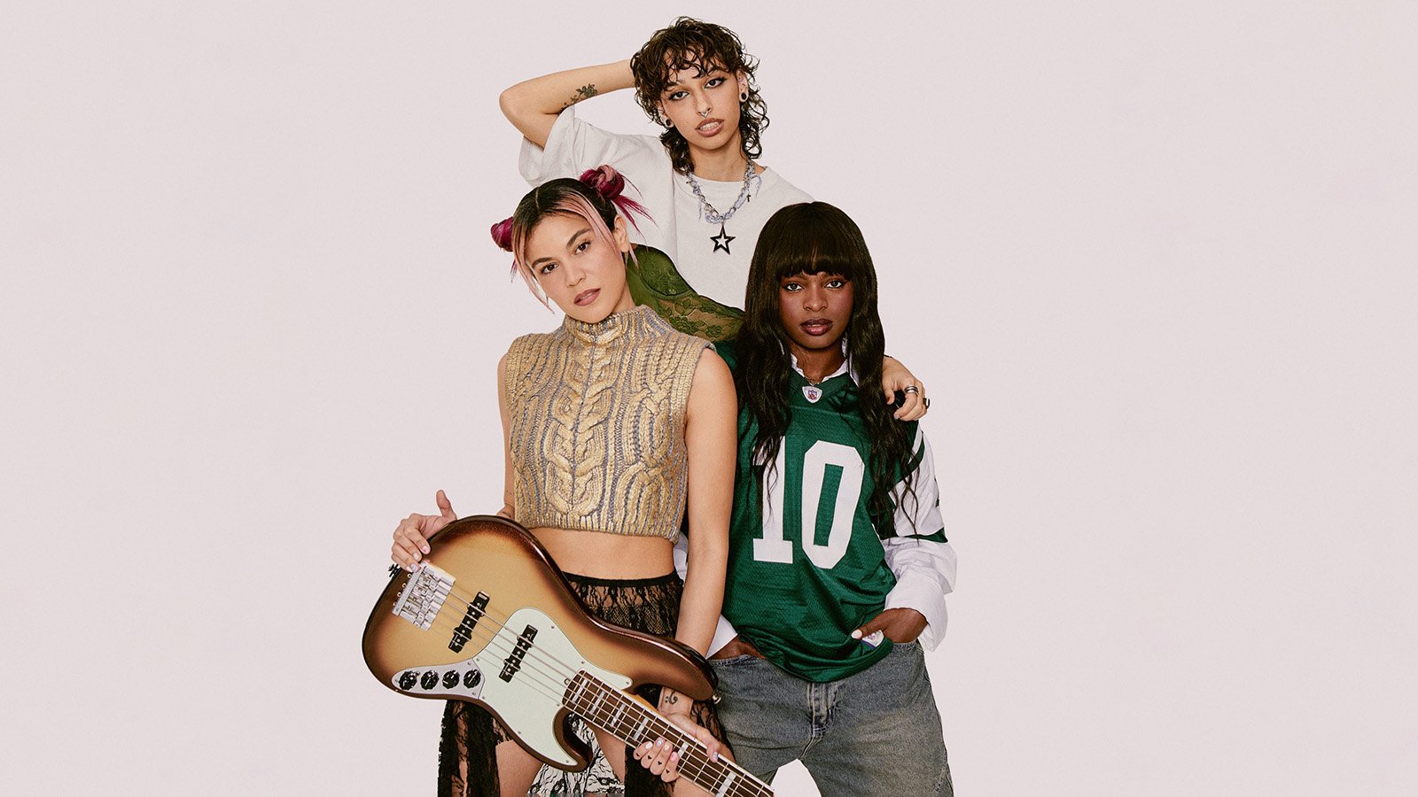 Three members of Darumas pose with a guitar